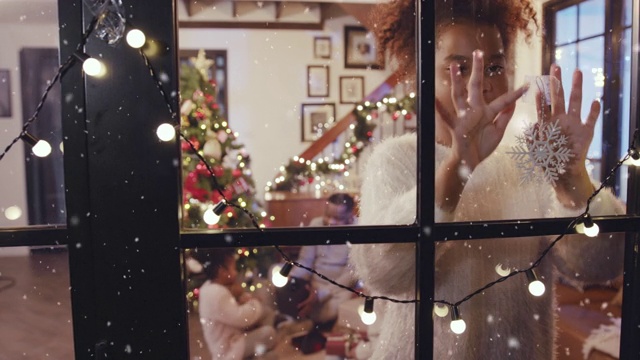 快乐的女孩一边在窗前装饰雪花，一边先下大雪，构思冬天和圣诞节的场景视频素材