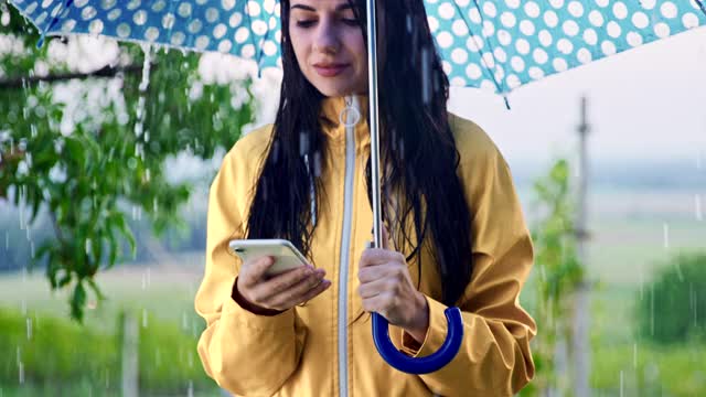 SLO MO女人在雨伞下使用她的智能手机视频下载