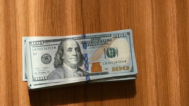 一叠百元美钞落在桌子上视频素材