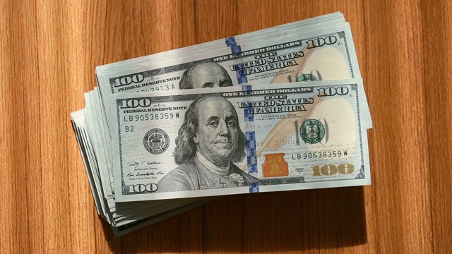 一叠百元美钞落在桌子上视频素材