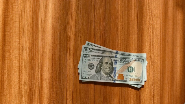 实时:一小撮百元美钞落在木桌上视频素材