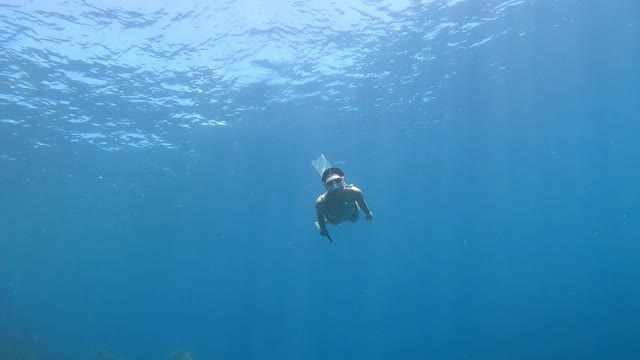 4K自由潜水长鳍海豚踢腿风格在大海的清澈的水后面的空气泡沫视频下载