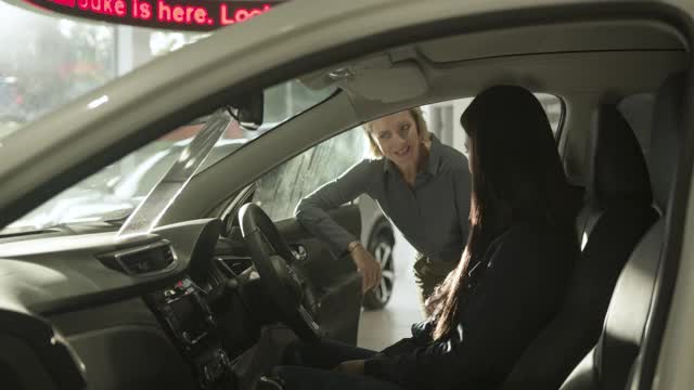 女性在汽车展厅试驾新型电动汽车，女销售员提供建议视频下载