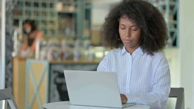 疲惫的非洲女商人与笔记本电脑在咖啡馆背痛视频素材