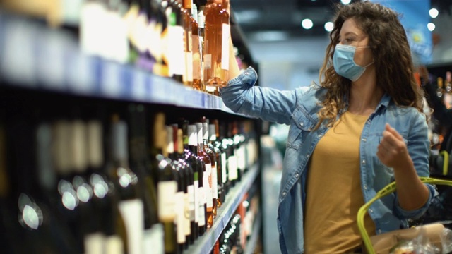 一名年轻女子在新冠肺炎大流行期间在超市买酒。视频素材