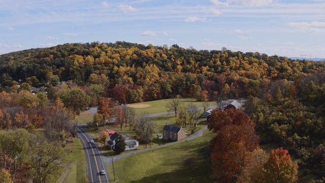 五彩缤纷的秋天在宾夕法尼亚州农村。从空中俯瞰里海镇附近的小村庄，群山之间被树林覆盖。航拍视频与平移摄像机运动。视频素材