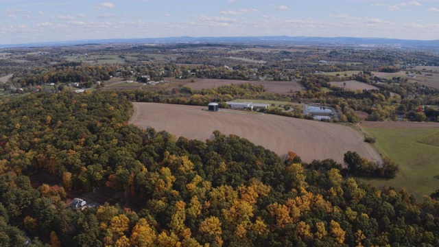 五彩缤纷的秋天在宾夕法尼亚州农村。航拍里海镇附近的农田，山与山之间的森林、拼凑的田野、村庄和农场。航拍视频与向后相机运动。视频素材