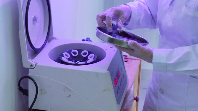 亚洲华裔女医生将血液样本放在离心机上。Covid-19血液测试视频下载