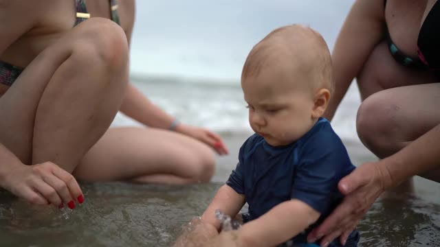 一家人在沙滩上照顾在沙滩上玩耍的婴儿视频下载