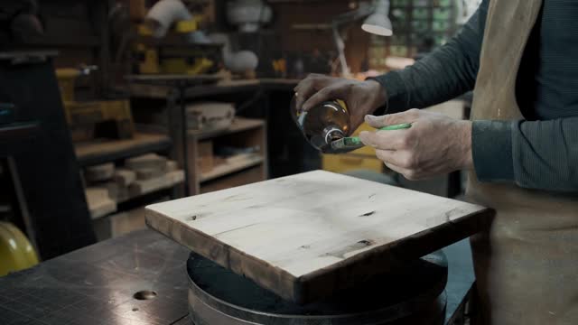 一个木匠用刷子为一个阁楼式的椅子画一块木头。近距离视频下载
