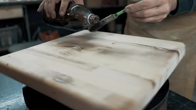 一个木匠用刷子为一个阁楼式的椅子画一块木头。近距离视频下载
