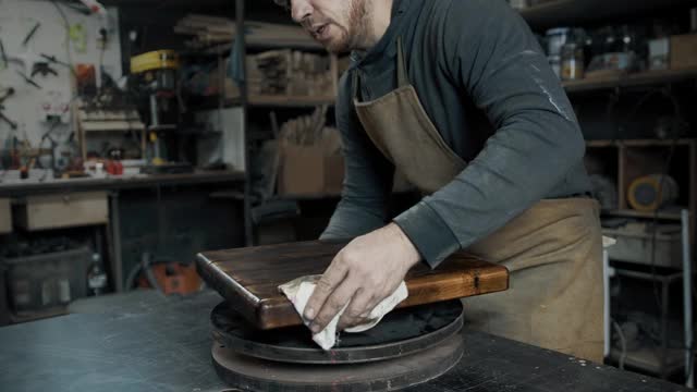 一个木匠正在用一块破布擦一块做高架椅子的木头视频下载