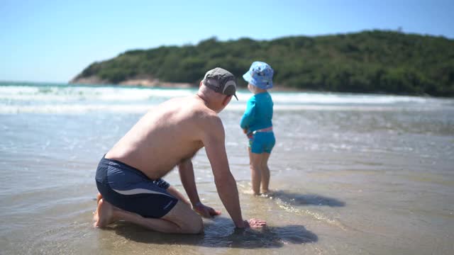 小男孩和他爷爷在海滩上玩视频下载