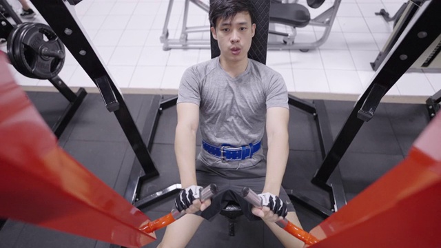 亚洲人工作在坐式手臂和肩部健身器在健身房。视频素材