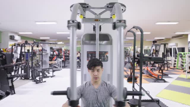 年轻的男运动员在健身俱乐部做坐式胸压。视频下载