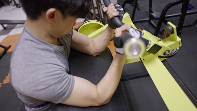 一个年轻人在健身房的二头肌健身器上锻炼视频素材