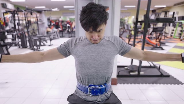 亚洲男子在健身房里做坐式胸压运动。视频素材