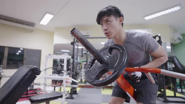 年轻运动员在健身房的运动器械上锻炼手臂和背部。视频素材
