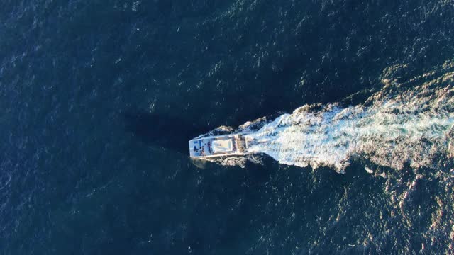 在澳大利亚新南威尔士州悉尼的曼利海滩附近，一艘客运渡轮正在进行周末观鲸之旅，航拍4k电影高角度无人机镜头。甲板上的人面目全非视频素材
