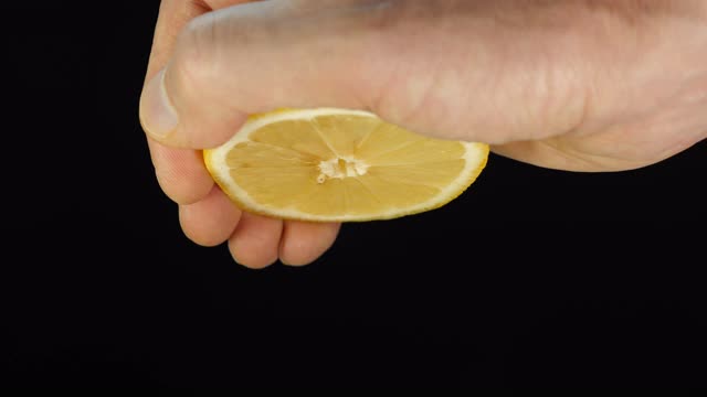 一个男人的手挤半个熟透的黄色柠檬，挤出几滴汁来视频素材