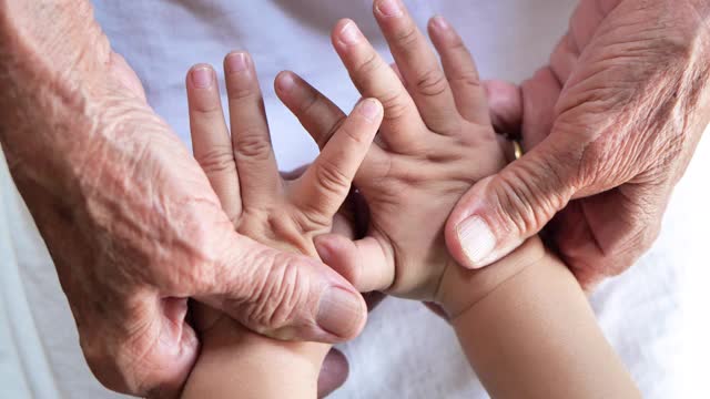 拉近祖母牵着孙子的手。爱家庭保健，医身体部份。祖父母的爱的概念。视频素材