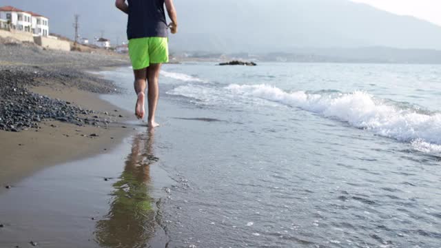 一个年轻人在海滩上慢跑视频素材