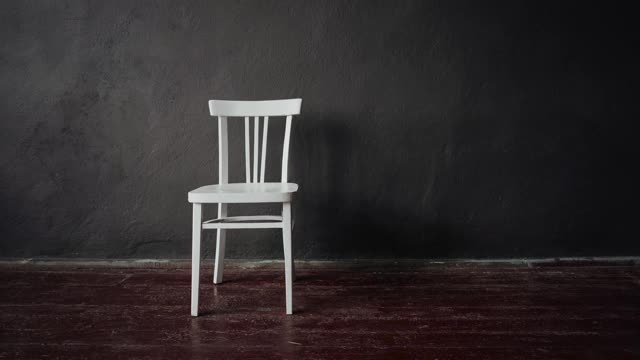 白色的椅子放在一个棕色地板，灰色墙壁的空房间里视频下载