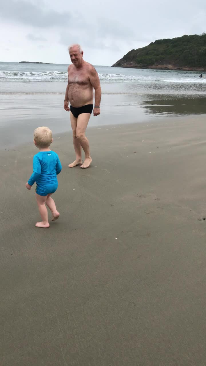 孙儿进入大海与祖父用手机拍摄视频下载