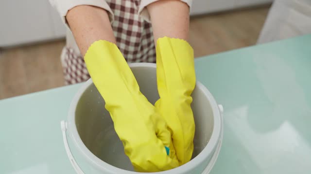 亚洲年轻的家庭主妇捻着湿抹布清洁厨房柜台。为了家里的卫生和健康，老妇人在做饭后在桌子上擦布。视频下载