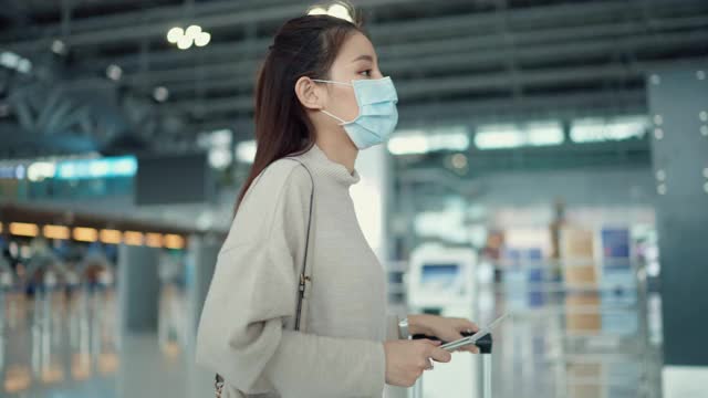 年轻女子戴着外科口罩早早来到机场为此行做准备。视频素材