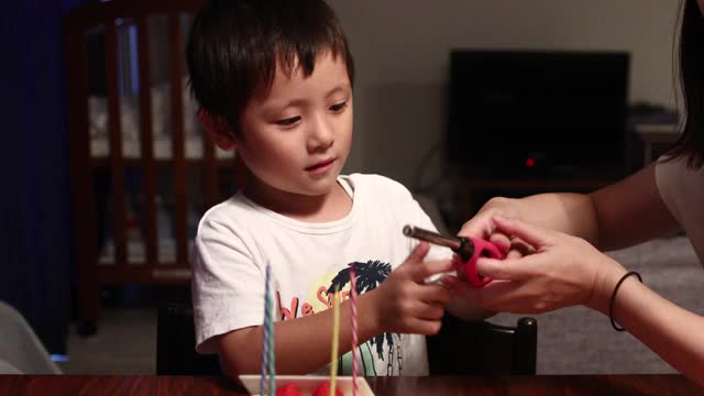 一个男孩和他的妈妈点燃了一支生日蛋糕蜡烛视频素材