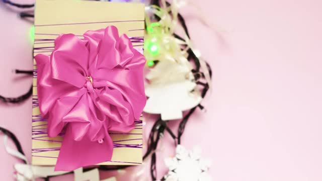 礼盒与一个大的粉红色蝴蝶结在粉红色的背景与一个花环。视频下载