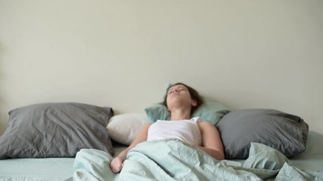 一个年轻女人睡过头了，突然从床上爬起来，跑去准备视频素材