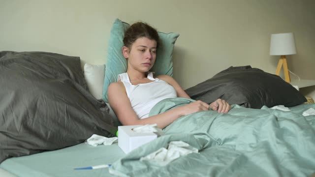 女人在床上吃药，用一次性手帕擤鼻子视频素材