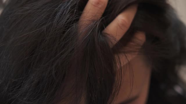 一位中年妇女用灰白的发根抚摸着她的黑发视频素材