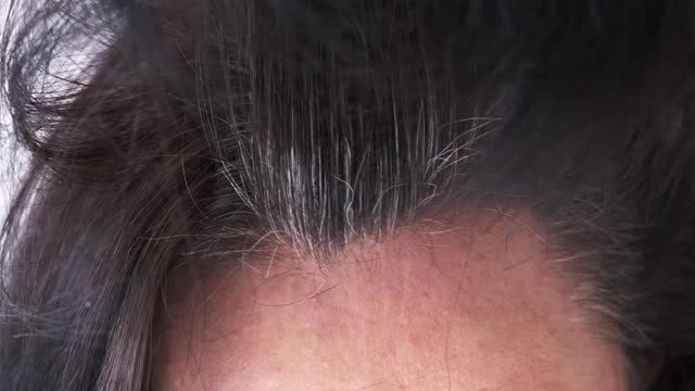 一位中年妇女用灰白的发根抚摸着她的黑发视频素材