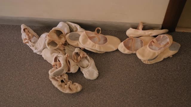 在舞蹈工作室的地板上有很多孩子的芭蕾舞鞋。视频下载
