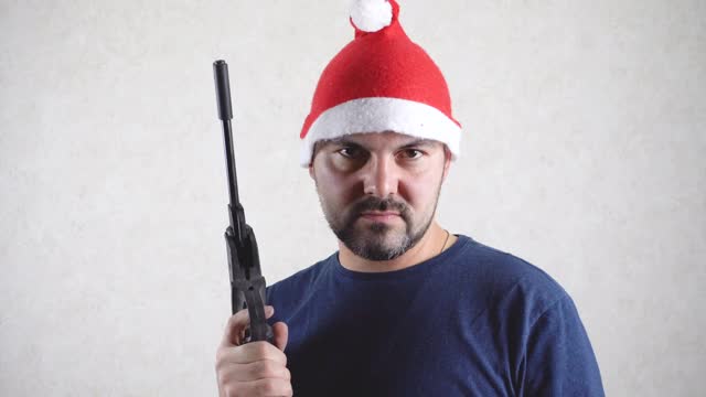 一个戴着圣诞帽，手里拿着手枪的严肃男人视频下载