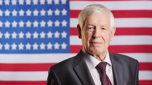 年长男性政治家在美国国旗上摆姿势的肖像视频下载