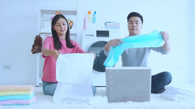 年轻夫妇在家里一起用自动洗衣机洗衣服和毛巾，他们一起打扫家里视频下载