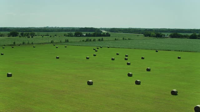 正在上升的无人机在堪萨斯州里昂县田野的干草堆上空飞行视频下载
