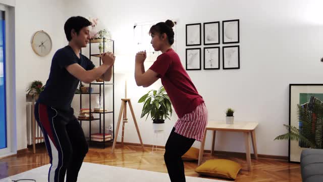 一对日本夫妇在隔离期间在家锻炼，在网上健身教练的指导下做深蹲视频下载