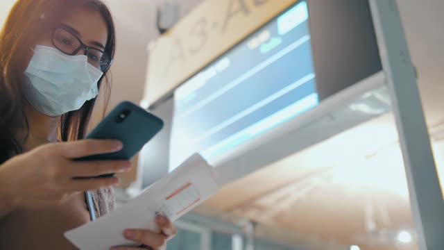 年轻的亚洲女子在机场航站楼使用智能手机视频素材