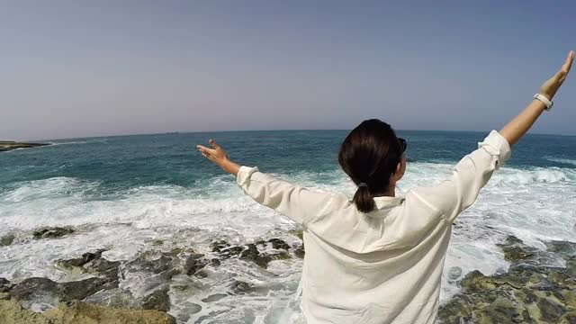 慢镜头:一个女人在美丽的天气站在海边呼吸新鲜空气视频素材