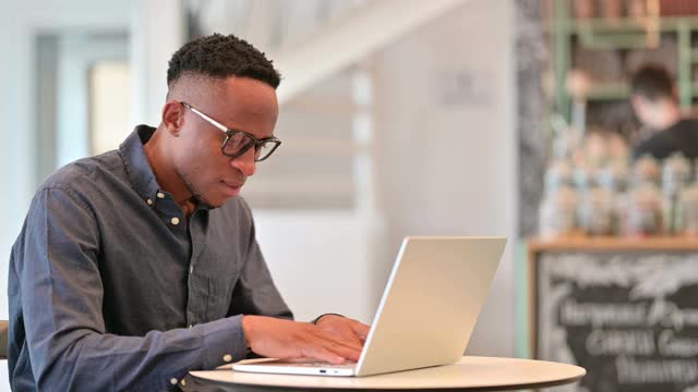 疲惫的非洲人与笔记本电脑有背痛在咖啡馆视频素材