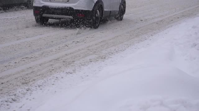 汽车在城市积雪的道路上行驶，慢镜头。运输，冬季轮胎，慢动作视频素材