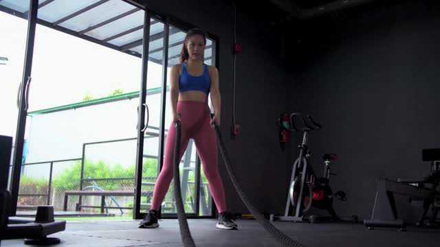 亚洲女运动员在体育馆里用格斗绳训练，以健康的生活方式决心健身，实现目标。视频素材