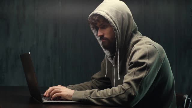 侧视图的危险集中的年轻大胡子男子黑客在线网站在黑暗的工作场所。视频素材