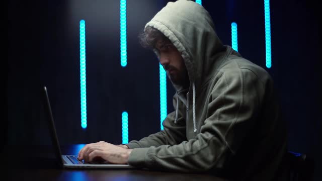 侧视图的高加索程序员黑客在线网站或密码坐在书桌在黑暗的房间，视频素材