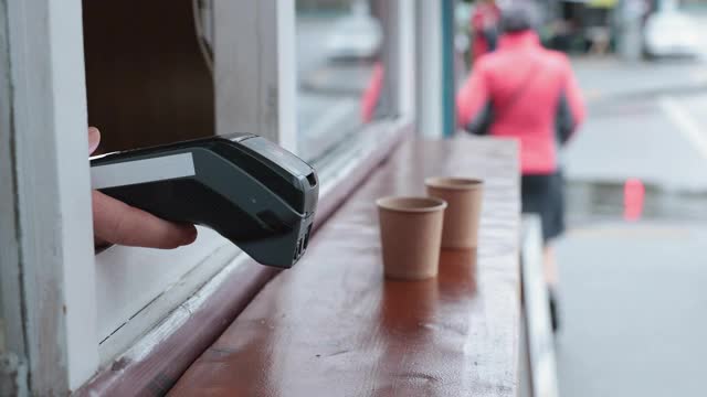 使用支付终端和智能手机在街头咖啡店购买咖啡的非接触式支付。视频下载